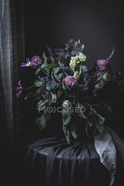 Buquê de flores em uma mesa no quarto vintage escuro — Fotografia de Stock