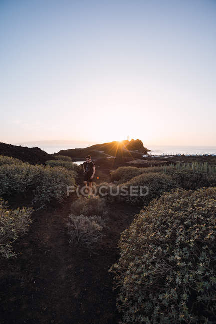 Fotografo maschio che cammina sul mare al tramonto — Foto stock