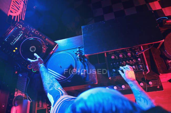 Close-up of anonymous dj man playing in a club with lights — Stock Photo