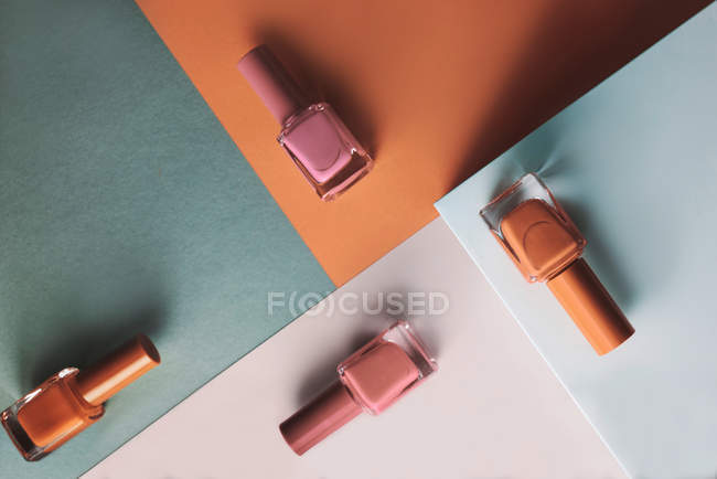 Разноцветные лаки для ногтей на фоне геометрических узоров — стоковое фото