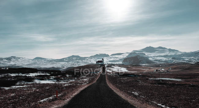 Церковна будівля, розташована біля чорнової сільської дороги проти хмарного неба в Ісландії — стокове фото