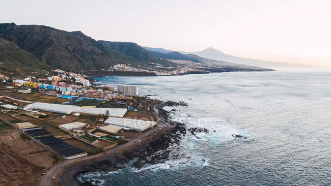 Aerial view of cityscape on majestic coastline at bottom of mountains of Tenerife, Spain — Stock Photo