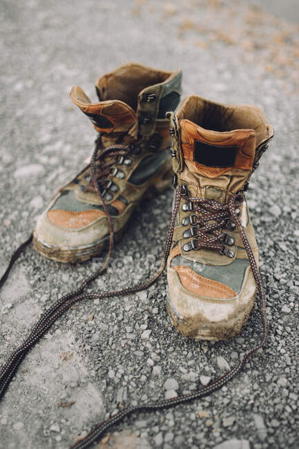 Pair of weathered hiking boots placed on stony road in countryside — Stock Photo
