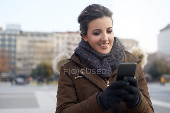 Giovane donna in abiti invernali con smart phone all'aperto a Milano — Foto stock