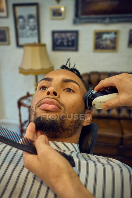 Close-up view of anonymous hairstylist grooming an african-american customer — Stock Photo