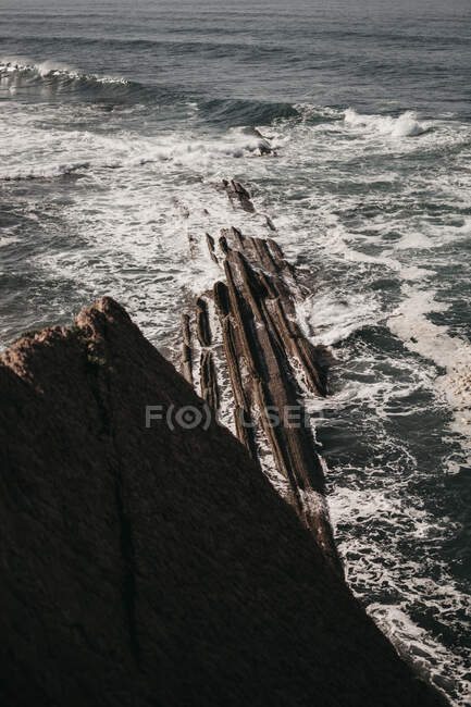 Schäumende Wellen von Meerwasser krachen in der Nähe felsiger Klippen in die Natur — Stockfoto