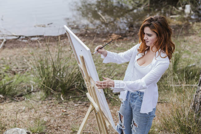 Jovem mulher pintura no campo — Fotografia de Stock