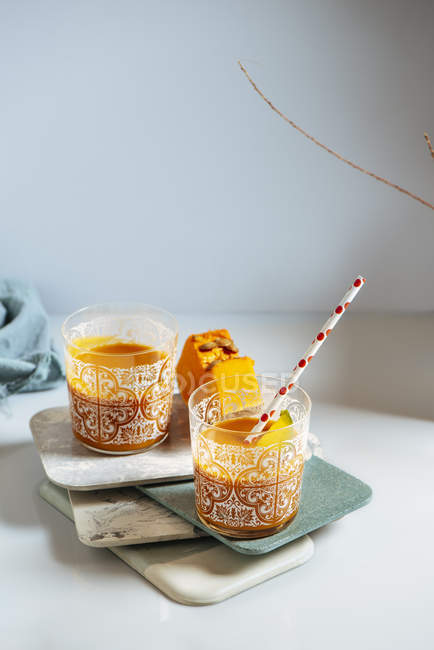 Mango und Kürbis Smoothie Gläser auf gestapelten Brettern — Stockfoto