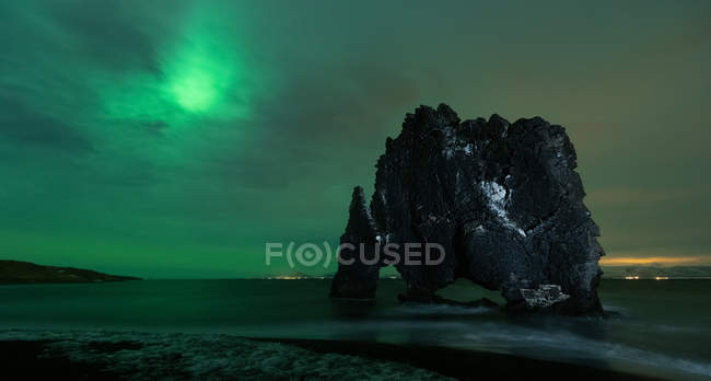 Pintoresca vista de la playa y la formación de rocas bajo las luces del norte del cielo en Hvtserkur Islandia - foto de stock