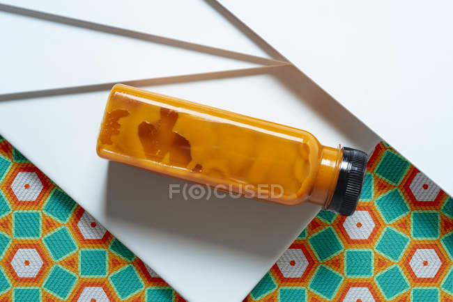 Botella de batido de mango y calabaza sobre textura geométrica de estilo retro - foto de stock