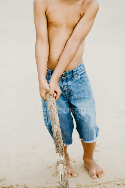 Raccolto ragazzo afroamericano con bastone giocare sulla riva sabbiosa vicino al mare — Foto stock