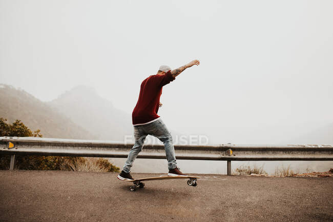 Trendy skateboarder doing trick in nature — Stock Photo