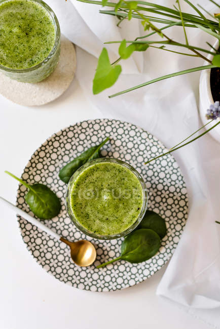 Smoothie verde saudável de espinafre, abacate e kiwi, maçã e limão em vidro em prato estampado — Fotografia de Stock