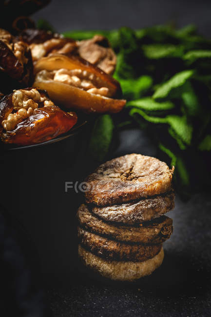 Halal snack for Ramadan with dried dates, figs, fresh mint and cinnamon on dark background — Stock Photo