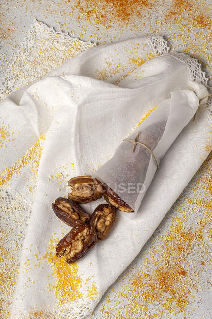 Snack halal para Ramadán con dátiles secos, higos y canela envueltos en papel sobre tela blanca - foto de stock
