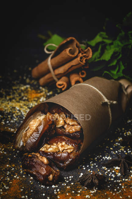 Крупный план халяльной закуски для Рамадана с сушеными финиками и грецкими орехами, завернутыми в пергамент — стоковое фото