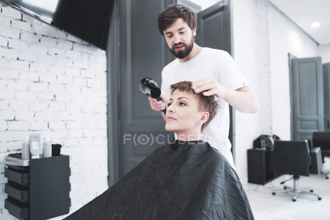 Перукарня сушить волосся жінці — стокове фото