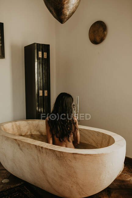 Seitenansicht einer hübschen Frau, die in einem rustikalen Haus badet — Stockfoto