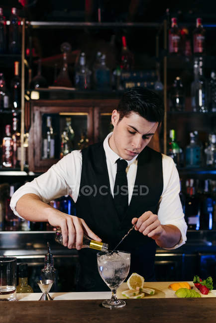 Молодий елегантний бармен працює за барною стійкою змішування напоїв з фруктами — стокове фото