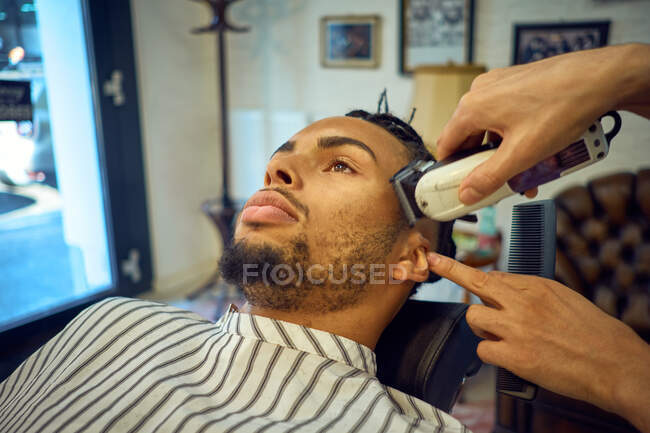 Close-up view of anonymous hairstylist grooming an african-american customer — Stock Photo