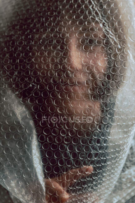 Femme regardant la caméra alors qu'elle est empêtrée dans un emballage à bulles — Photo de stock