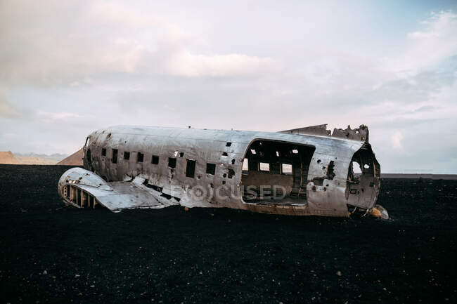 Carcaça de avião batido localizado no chão preto do campo desolado no dia nublado — Fotografia de Stock