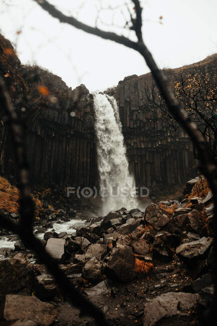 Pintoresca vista de la cascada increíble y el acantilado áspero en el día gris en el hermoso campo - foto de stock