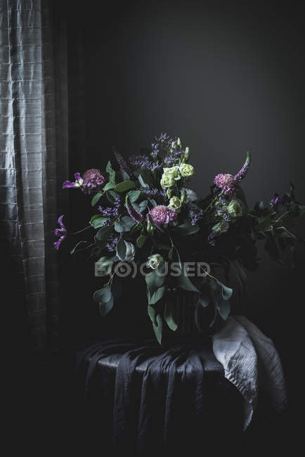 Buquê de flores em uma mesa no quarto vintage escuro — Fotografia de Stock