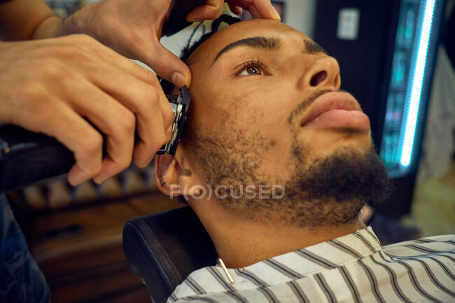 Vista da vicino del parrucchiere anonimo che cura un cliente afro-americano — Foto stock