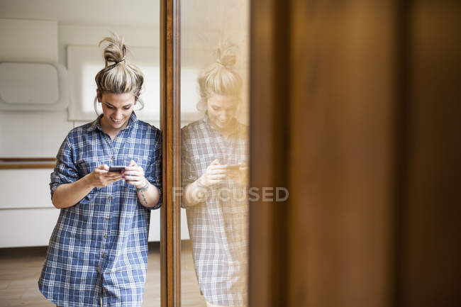 Bella e giovane donna divertirsi e chattare con lo smartphone nella sua casa — Foto stock