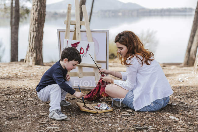 Мать и мальчик рисуют на озере — стоковое фото