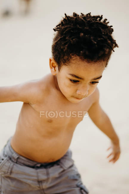 Engraçado menino afro-americano jogando na costa arenosa perto do mar — Fotografia de Stock