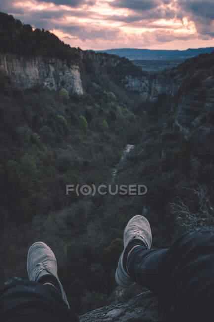 Вид на невелику річку в каньйоні і ноги людини, що сидить на краю — стокове фото