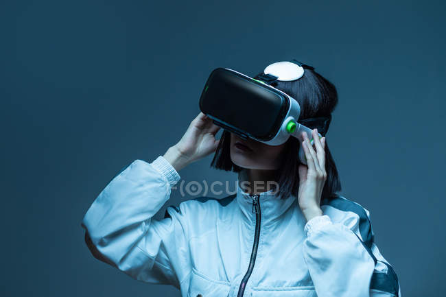 Jeune femme excitée ayant une expérience de réalité virtuelle sous la lumière du néon — Photo de stock