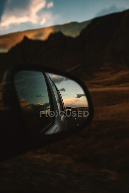 Размышления на асфальтовой сельской дороге и величественном небе заката в зеркале крыла неба во время путешествия по природе — стоковое фото