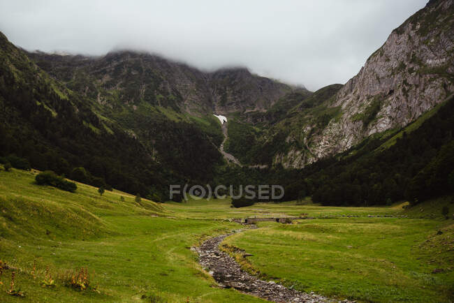 Beautiful mountains located around calm valley with green grass on cloudy day in amazing countryside — Stock Photo