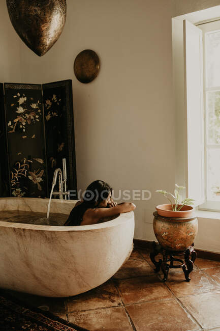 Vista lateral da mulher bonita tomando banho em uma casa rústica — Fotografia de Stock