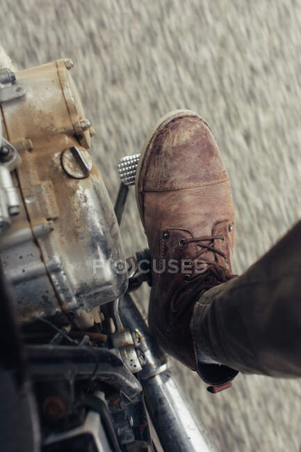 Leg of anonymous man stepping on pedal of motorbike during ride on asphalt road — Stock Photo