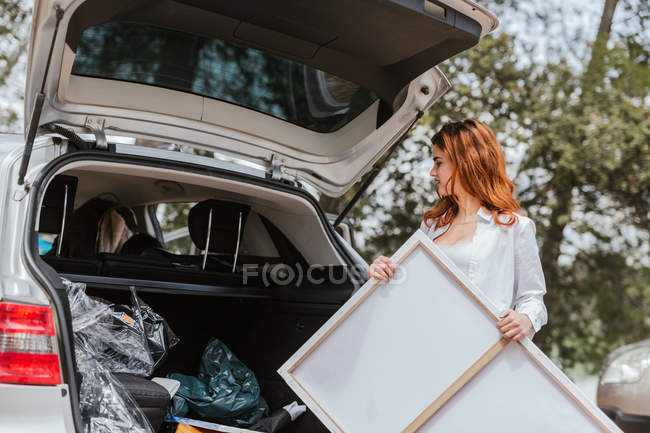 Female artist taking canvas from car — Stock Photo