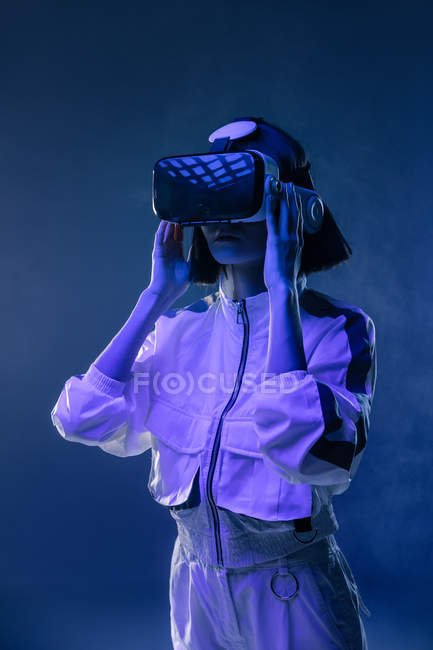 Mujer joven emocionada teniendo experiencia de realidad virtual en luz de neón - foto de stock