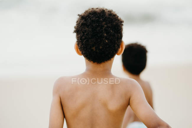 Dos hermanos afroamericanos jugando juntos en la orilla arenosa cerca del mar - foto de stock