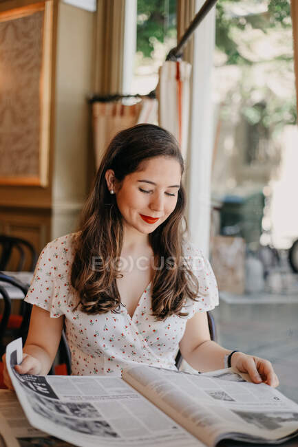 Jovem senhora bonita lendo um jornal em um café vintage — Fotografia de Stock
