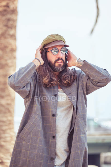 Homem barbudo elegante com cabelos longos em pé na rua — Fotografia de Stock