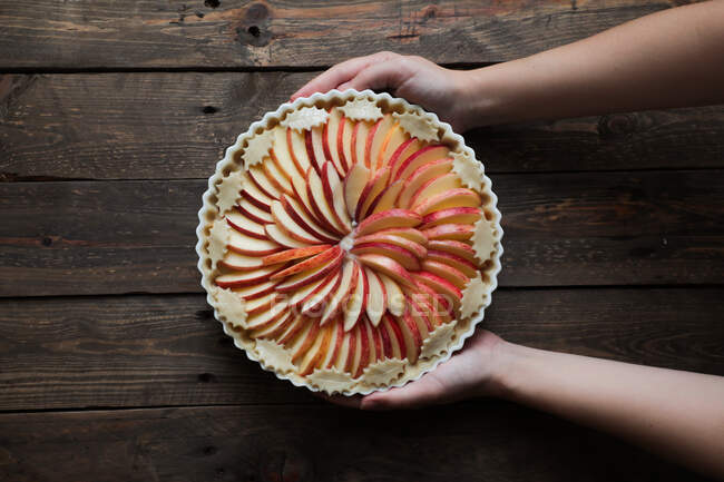 Unerkennbare Frau zeigt leckeren Apfelkuchen auf Holztisch — Stockfoto