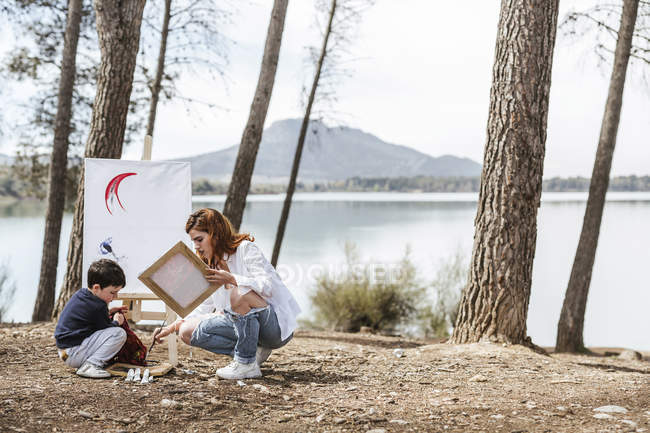 Mother and boy painting near lake — Stock Photo
