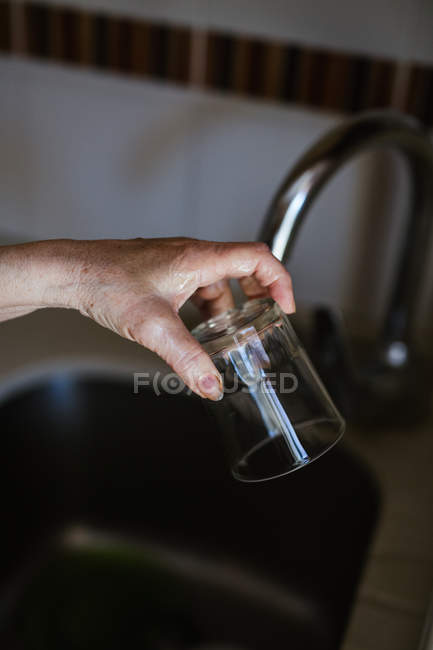 Обрезанный образ женщины, стоящей возле раковины и мытья стекла с мылом в кухне дома — стоковое фото