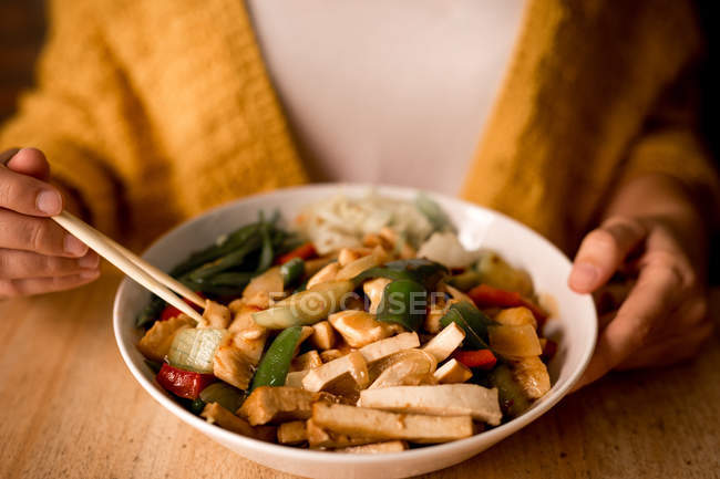 Primo piano della donna che mangia ciotola di gustoso piatto vegetariano con verdure — Foto stock