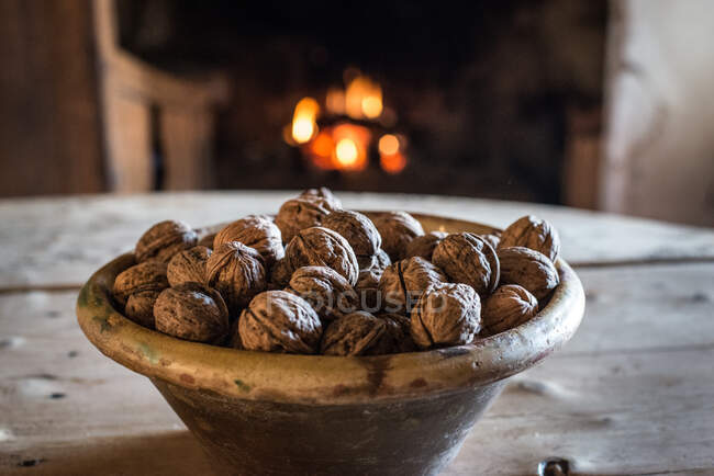 Bol de noix bio naturelles sur table en bois près de la cheminée dans une ancienne maison de village — Photo de stock