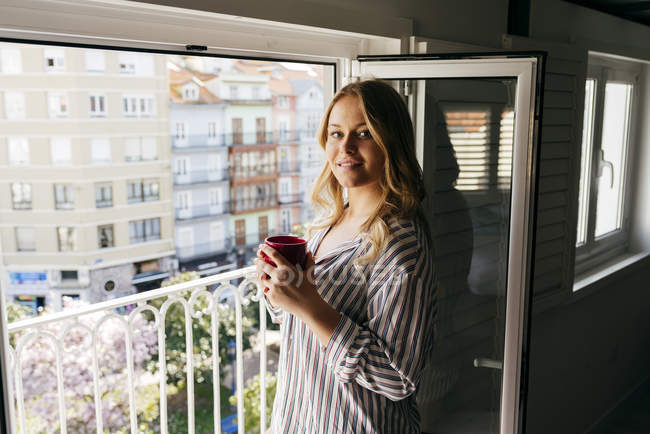 Young woman with cup looking at camera — Stock Photo