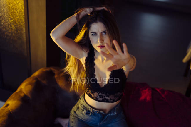 Young seductive female gesturing stop sign on couch at home — Stock Photo